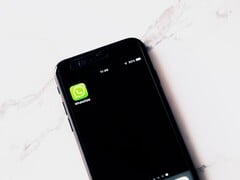Смартфон на белом столе с открытым приложением WhatsApp
