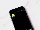 Смартфон на белом столе с открытым приложением WhatsApp