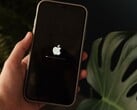 На экране видна рука, держащая iPhone; на экране светятся логотип Apple и индикатор выполнения.