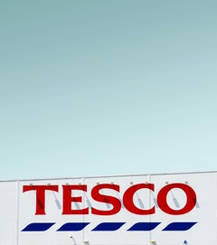 Внешняя вывеска Tesco сфотографирована на фоне ясного неба (Источник изображения: Simone Hutsch via Unsplash)