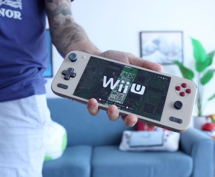 Расс из Retro Game Corps держит в руках портативную консоль Ayaneo Pocket S2 с эмулятором Wii U; устройство изображено на видном месте в гостиной. (Источник изображения: Retro Game Corps)