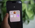 Рука держит смартфон, на экране которого видна папка с названием «AI», содержащая приложения Gemini, ChatGPT и Claude
