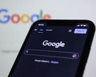 Смартфон с открытой страницей поиска Google перед экраном с логотипом Google