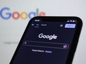 Смартфон с открытой страницей поиска Google перед экраном с логотипом Google