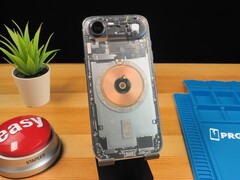 Прозрачный iPhone Air показывает внутренние компоненты и медную катушку зарядки на деревянном столе. (Источник изображения: Phone Repair Guru via YouTube)
