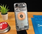 Прозрачный iPhone Air показывает внутренние компоненты и медную катушку зарядки на деревянном столе. (Источник изображения: Phone Repair Guru via YouTube)