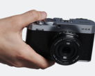 Компактная фотокамера со сменными объективами Fujifilm X-E4 в руках
