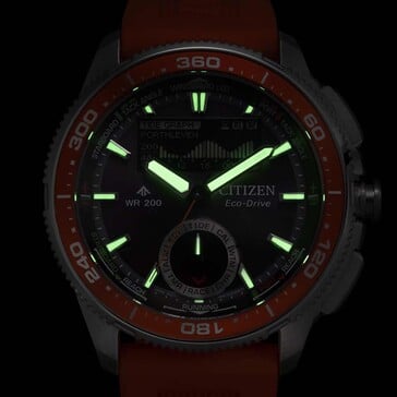 Снимок часов Citizen Promaster Wave Tracker JV3000-13E с люминесцентным освещением в условиях низкой освещенности демонстрирует светящиеся стрелки и часовые метки на темном фоне.