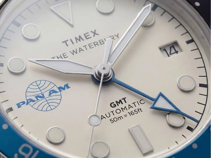 Крупный план часов Timex Pan Am Waterbury Automatic GMT, на котором видны их серебристо-белый циферблат, светящиеся часовые метки, окошко даты и логотип Pan Am.