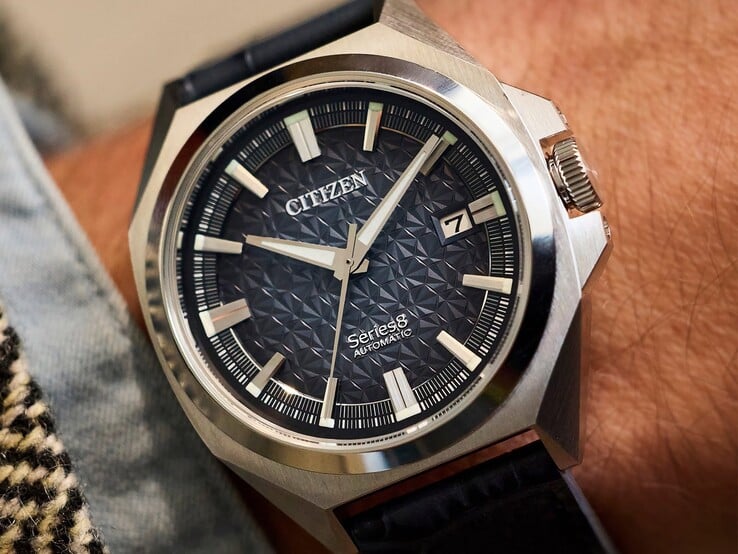 Автоматические часы Citizen серии 8 модели 831 с геометрическим циферблатом цвета жжёного оранжевого и коричневого, корпусом и безелем золотистого оттенка, а также интегрированным браслетом H-link золотистого оттенка, надетые на запястье.