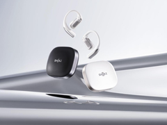 Shokz OpenFit Pro (с чехлом), изображенный на стилизованном серебряном фоне. (Источник изображения: Shokz)