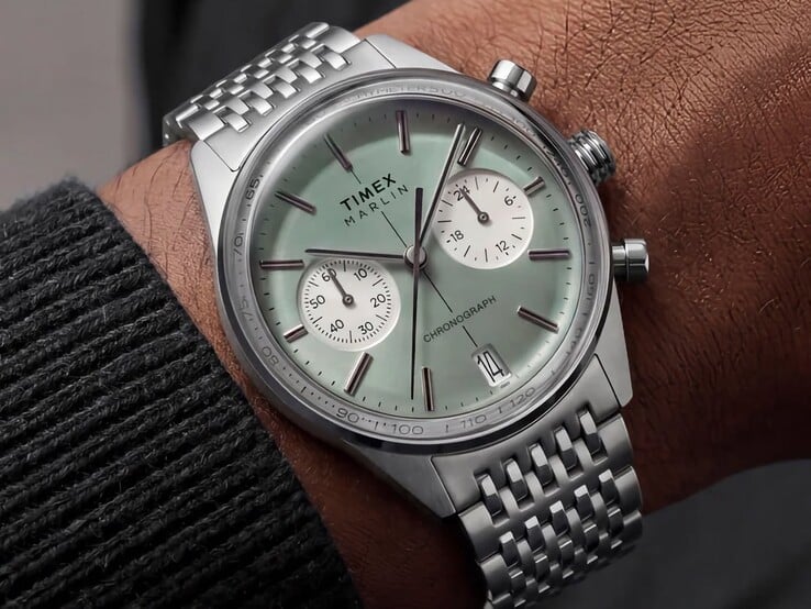 Хронограф Timex Marlin Jet с циферблатом цвета шалфея и браслетом из нержавеющей стали, надетый на запястье, демонстрирующий выпуклое стекло и закругленный ретрофутуристический профиль корпуса.