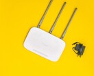 Белый Wi-Fi-роутер с тремя антеннами и блоком питания на желтом фоне