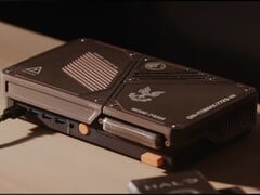 Специально разработанная компактная игровая консоль с мини-ПК, открытыми вентиляционными отверстиями, USB-портами и оранжевыми кнопками питания, расположенная на столе.