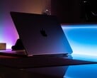 Наполовину открытый MacBook в тёмной комнате; свет проникает через щель и падает на стол