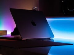 Наполовину открытый MacBook в тёмной комнате; свет проникает через щель и падает на стол