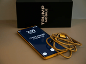 Фотография телефона Trump Phone T1 вместе с коробкой и кабелем.