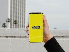 Рука, держащая смартфон с крупно отображённым словом «eSIM» на жёлтом экране.