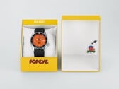 Автоматические часы Seiko 5 Sports x Popeye HDB013 с оранжевым циферблатом, расположенные рядом с желтой подарочной коробкой ограниченной серии.