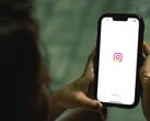 Женщина, держащая смартфон обеими руками; на экране отображается стартовый экран Instagram
