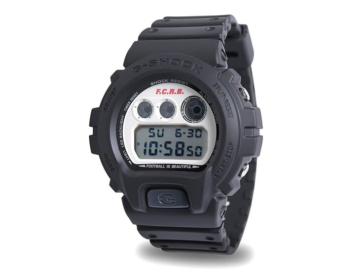 Вид под углом на цифровые часы Casio G-Shock DW-6900 x F.C. Real Bristol, выпущенные ограниченной серией, с черным ремешком из смолы и циферблатом кремового цвета в винтажном стиле.