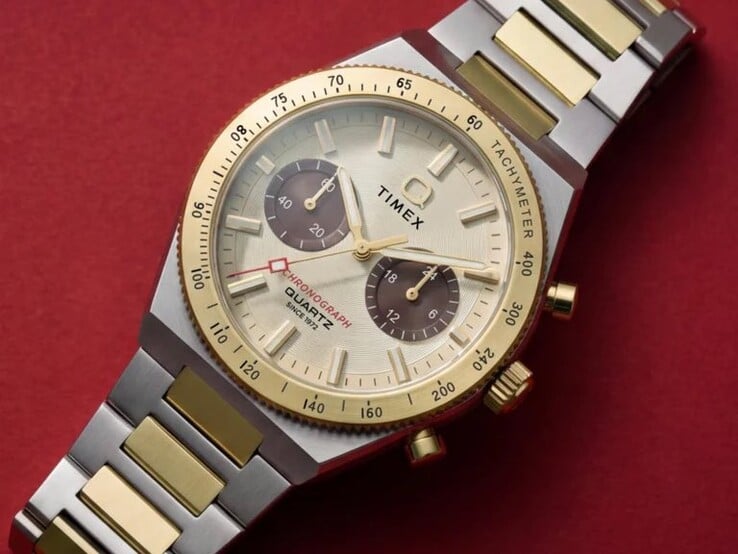 Крупный план часов Timex Q Timex Continental Chronograph TW2Y92300 на запястье, на котором видны циферблат золотистого оттенка, коричневые дополнительные циферблаты, безель с тахиметром и двухцветный браслет из нержавеющей стали.