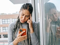 Женщина с серьёзным выражением лица смотрит на свой смартфон