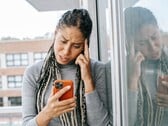 Женщина с серьёзным выражением лица смотрит на свой смартфон
