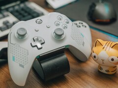 Белый контроллер Xbox лежит на деревянном столе рядом с маленькой фигуркой кошки (Источник изображения: FOX ^.ᆽ.^= ∫ via Pexels)