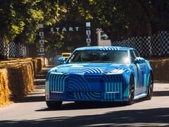 Электромобиль Jaguar Type 01 в камуфляжной расцветке «Blue Exuberant Modernism» мчится мимо стартовой решетки на гонке Goodwood Hill Climb